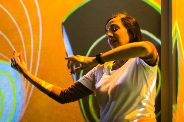 A woman using sign language to communicate with visitors in the FRAMELESS immersive gallery.