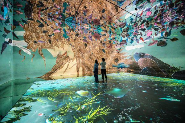 Two people standing inside FRAMELESS immersive art experience.